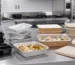 Barquettes alimentaires en plastique, aluminium, carton et fibre moulée avec couvercles dans une cuisine professionnelle.