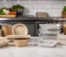 Contenants en fibre moulée, carton et aluminium comparés sur le plan de travail d’une cuisine professionnelle.