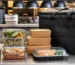 Contenants repas scellés et sac isotherme préparés sur le passe d’une cuisine professionnelle pour une livraison à domicile.